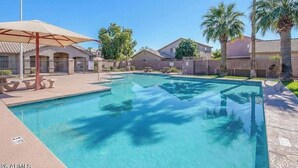 A swimming pool with a clear blue water, surrounded by palm trees and houses. - 3BR w patio, community pool, dog friendly (Chandler)