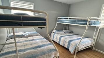 A room with two bunk beds, a ceiling fan, and a window with blinds.