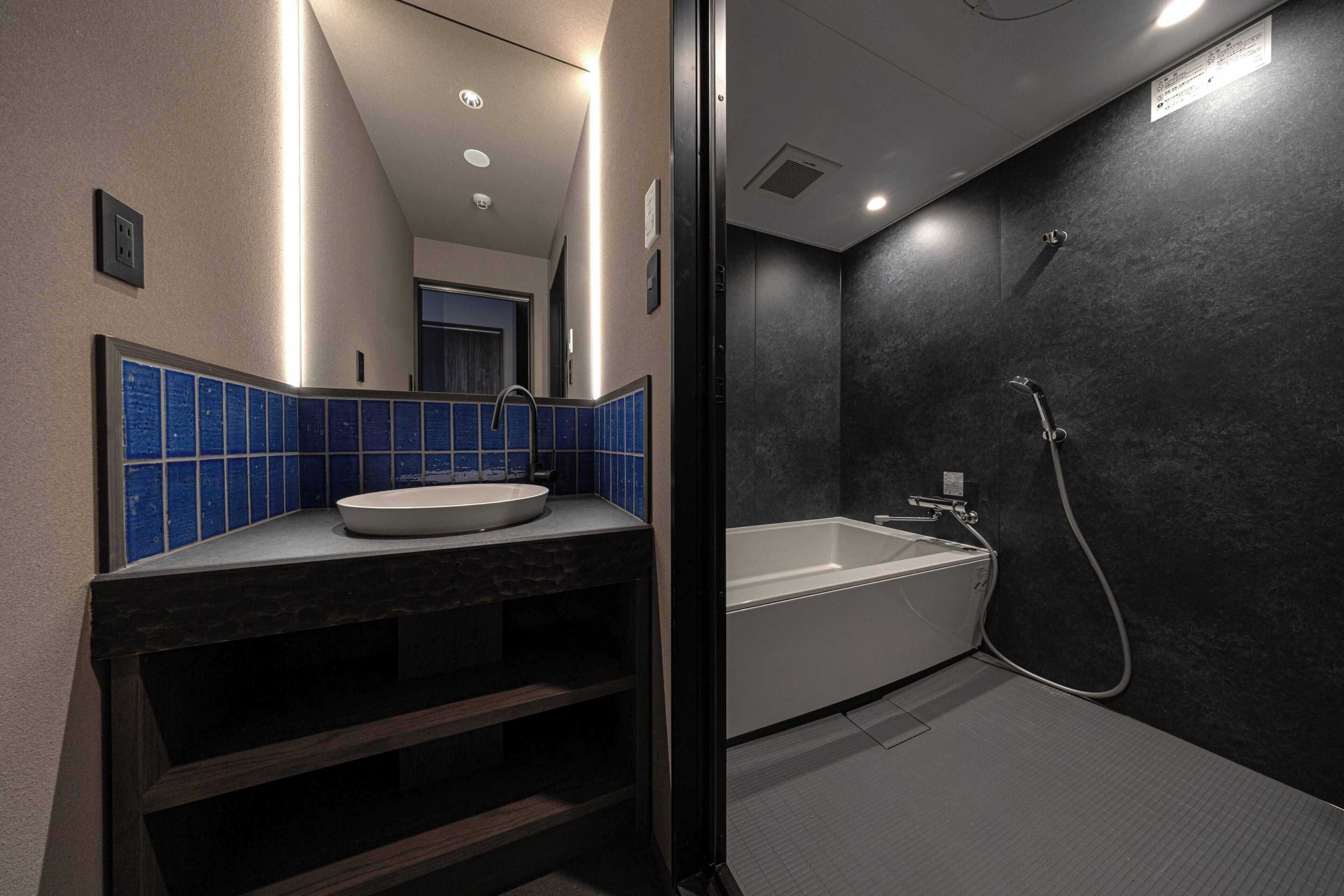 Une salle de bain moderne avec un lavabo blanc, un pare-feu en carreaux bleus et une baignoire sur pieds.