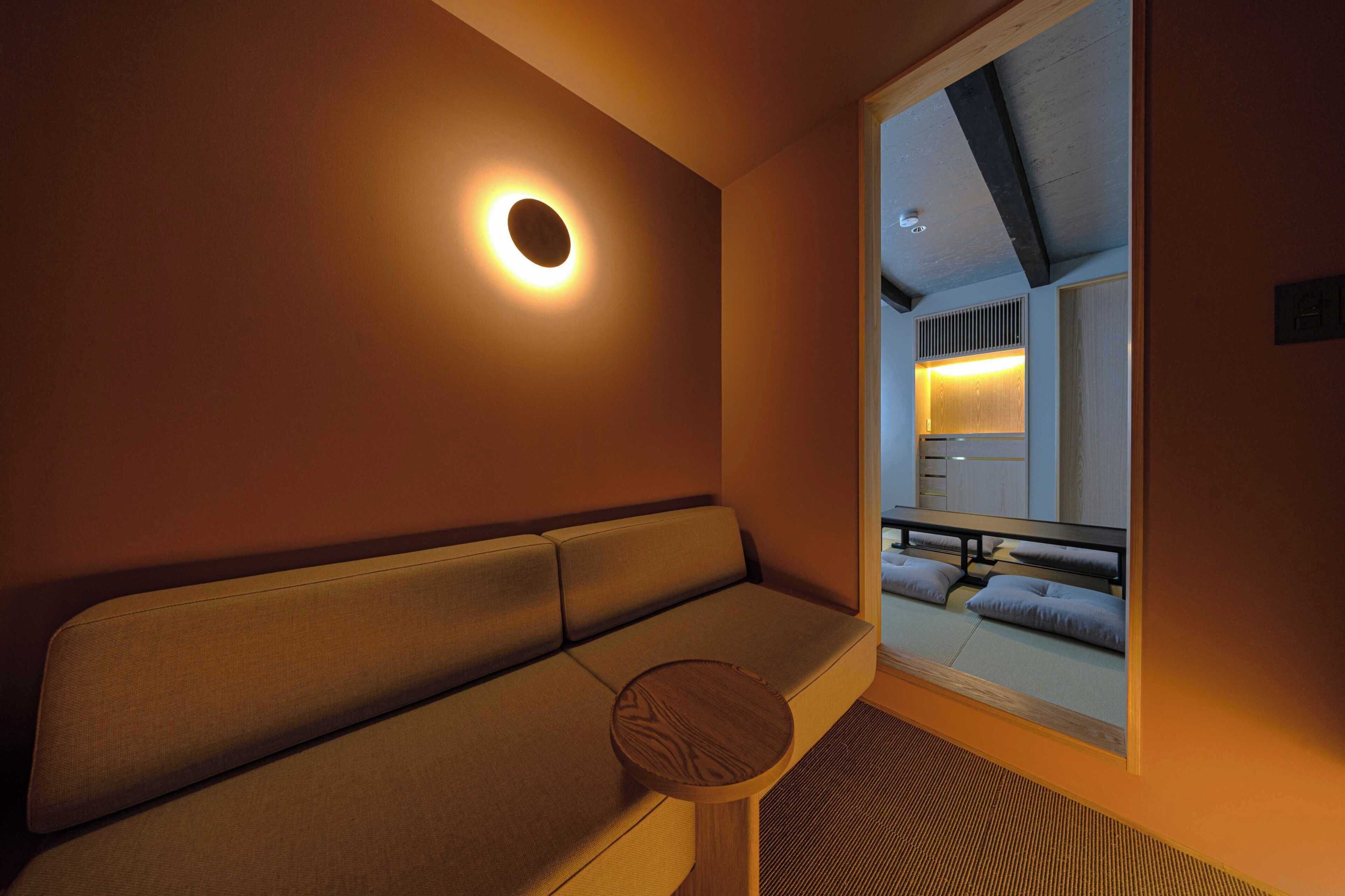 Une chambre d’hôtel moderne, dotée d’un canapé, d’une petite table ronde et d’une grande fenêtre donnant sur la cour intérieure.