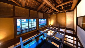 Una habitación japonesa tradicional con suelo de tatami, vigas de madera y puertas correderas.