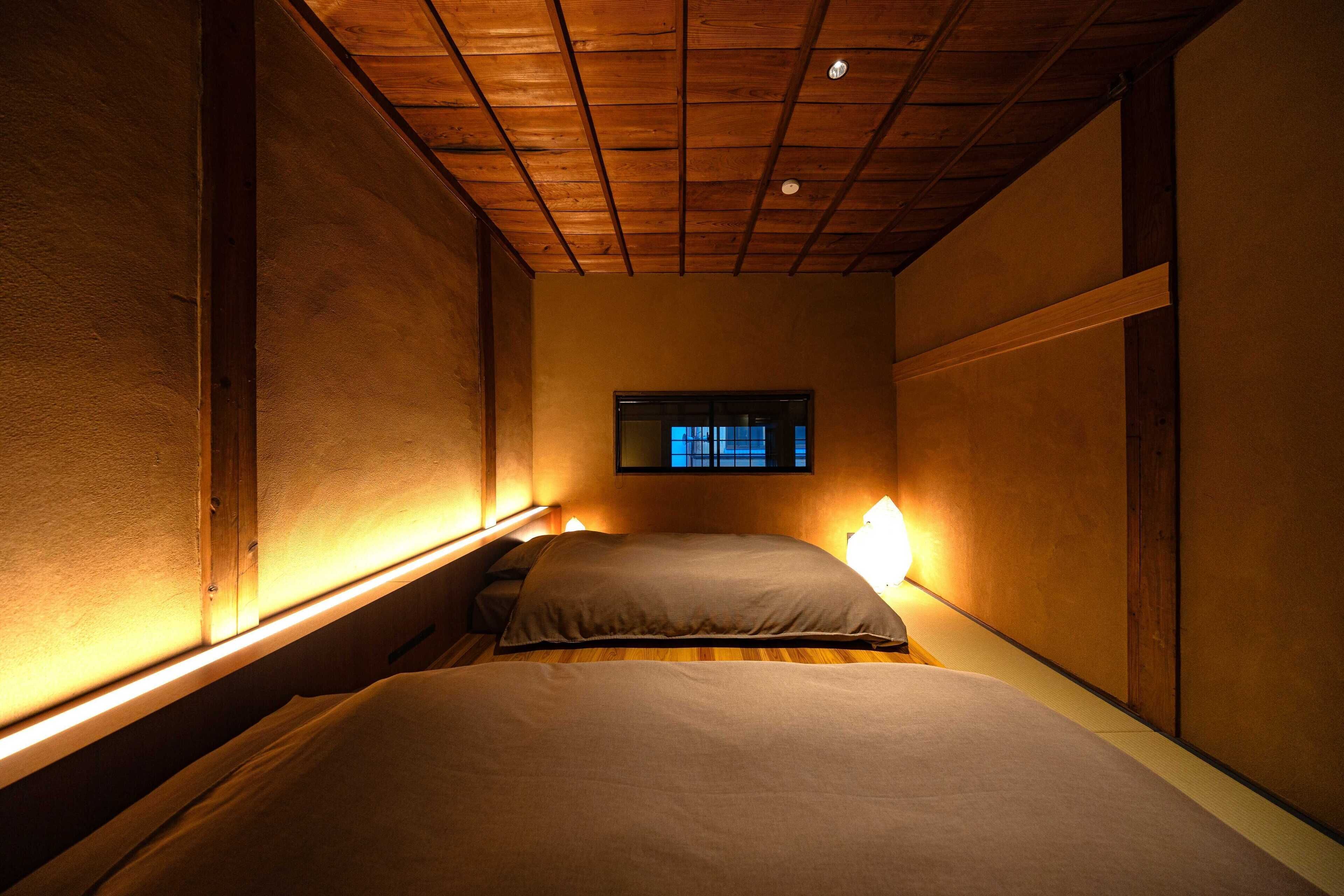 Una habitación estrecha con una cama individual, techo de madera y una ventana pequeña.