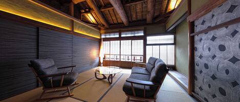 Una habitación japonesa tradicional con suelo de tatami, mobiliario de madera y vistas a través de amplios ventanales.