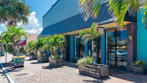 A commercial building with a blue exterior, large glass windows, and outdoor seating area with potted plants. - Gorgeous Oceanfront Retreat — Large Private Balcony, Private Beach Access & Pet-Friendly! ☀️ (Cocoa Beach)