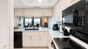 Una cocina moderna con armarios blancos, un microondas negro y un horno empotrado.