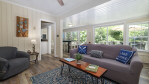 A living room with a sofa, coffee table, and a rug. There is a door leading to a balcony with outdoor furniture. - Dog-Friendly Lakeside Escape w/ Hammock & Fire Pit (Bahama)