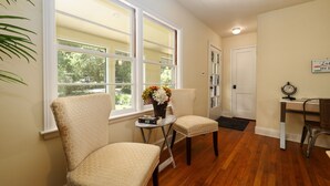 A room with two chairs, a small table with a vase of flowers, a desk with a clock, and a door. - Dog-Friendly Lakeside Escape w/ Hammock & Fire Pit (Bahama)