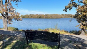 A park bench with a drawing of a sunset and trees, surrounded by trees and a lake. - Quiet wake cabin in Crowder (Crowder)