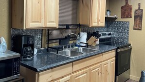 A kitchen with wooden cabinets, a black countertop, a coffee maker, and a stove. - Quiet wake cabin in Crowder (Crowder)