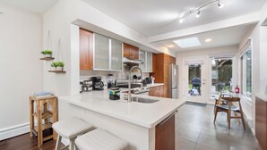Een moderne keuken met een groot eiland, houten kastjes en uitzicht op de achtertuin.