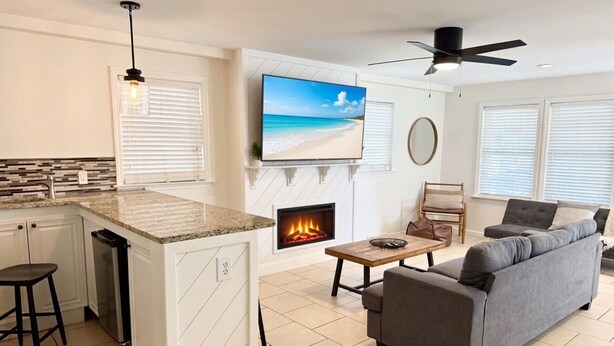 Una cocina moderna con una isla integrada, una chimenea, un televisor de pantalla plana y un ventilador de techo.
