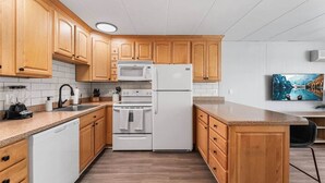 Une cuisine moderne avec des meubles en bois, des appareils électroménagers blancs et un plan de travail en granit.
