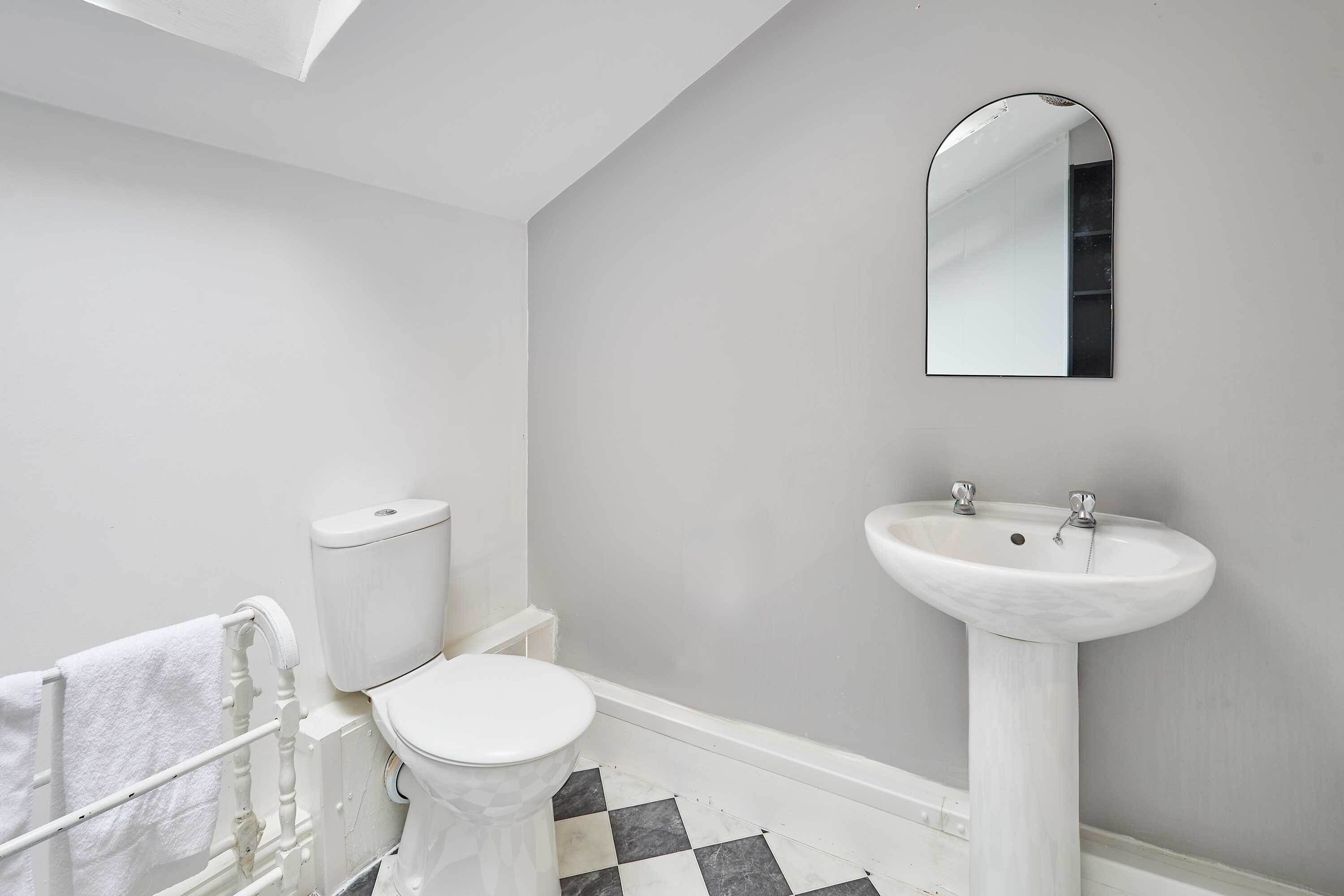 A bathroom with a toilet, sink, and a towel rack.