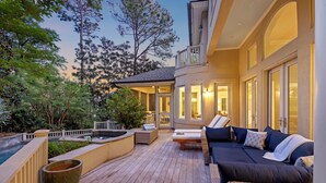 A deck with outdoor seating, a hot tub, and a view of trees.