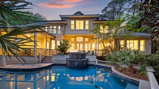 A large house with a swimming pool, a fountain, and a well-lit exterior.