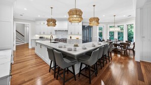 A spacious kitchen with a large island, white cabinetry, and a dining area with chairs.