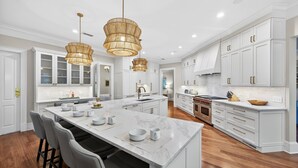 A modern kitchen with white cabinetry, a large island, and pendant lighting.