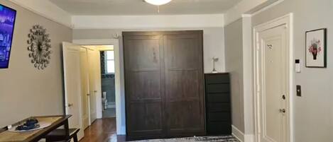 A room with a ceiling fan, a wooden door, a dark wooden cabinet, and a patterned rug.