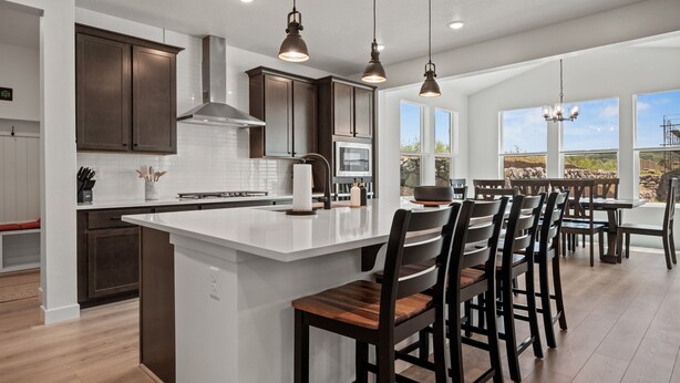A modern kitchen with dark cabinets, a large island, and pendant lighting. - Mountain Green Haven R2 | Ski Snowbasin | Hot Tub (Mountain Green)