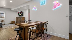 Eine moderne Küche mit einem Holztisch, Metallstühlen und einer Neonreklame an der Wand.