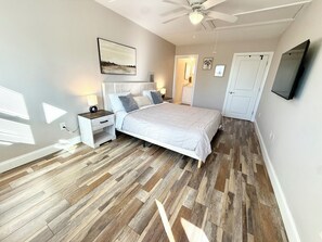 Ein Schlafzimmer mit Bett, Nachttischen, einem Deckenventilator und einem Bild an der Wand.