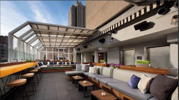 Eine Dachterrasse mit Glasüberdachung, Sitzbereichen und einer Bar.
