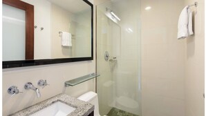 Ein modernes Badezimmer mit einer Duschkabine aus Glas, einem Waschbecken mit Natursteinplatte und einem Spiegel mit Holzrahmen.