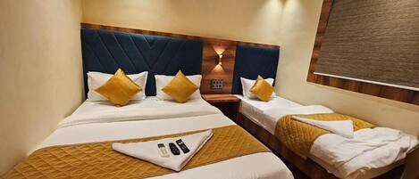 A hotel room with two beds, each with a wooden headboard, white bedding, and yellow pillows. There is a small table with a remote control and a tray.