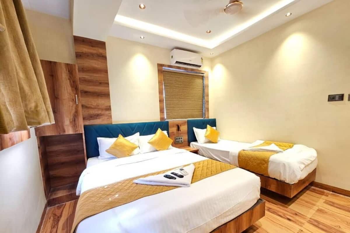 Une chambre d’hôtel avec deux lits, un plancher en bois, un luminaire au plafond et un appareil de climatisation.