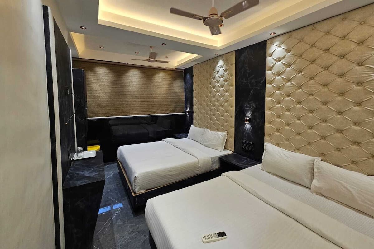 Une chambre d’hôtel moderne équipée de deux lits, d’une grande télévision à écran plat, d’un ventilateur de plafond et d’un sol en marbre.
