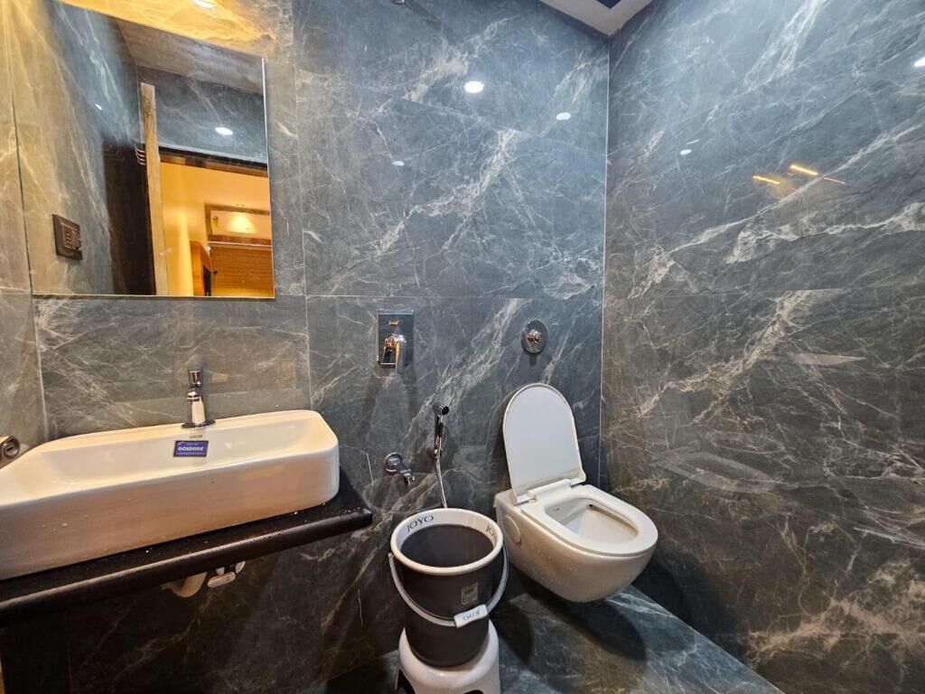 A bathroom with a marble wall, a sink, a toilet, and a bidet.