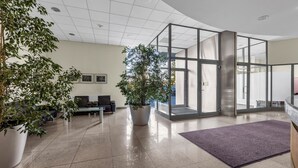 A modern lobby with a glass partition, a reception desk, and potted plants. - Bukowińska 22A Apartment with Terrace (Warszawa)