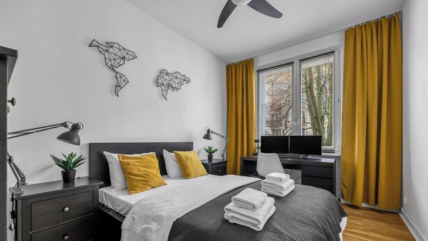 Un dormitorio moderno con cama, mesitas de noche, escritorio y televisor.