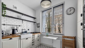Una cocina moderna con armarios blancos, encimera de madera, estufa integrada y ventana con persianas.