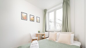 Et hotelværelse med en seng, et skrivebord og en stol. Tre billeder hænger på væggen.