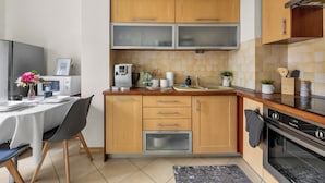 Une cuisine moderne avec des meubles en bois, un four encastré, un four à micro-ondes et un coin repas avec une table dressée pour deux personnes.