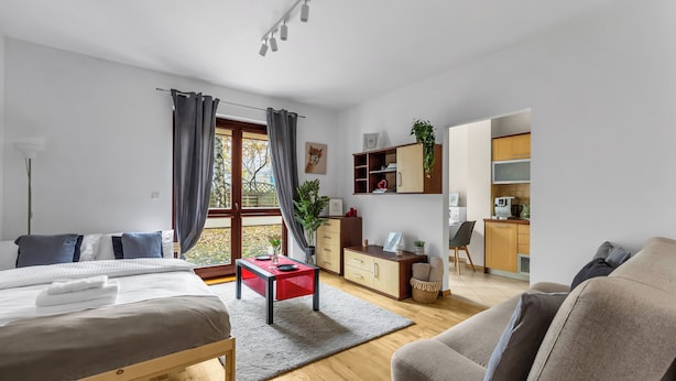 Une chambre à coucher moderne avec un lit, une table rouge et un canapé gris.