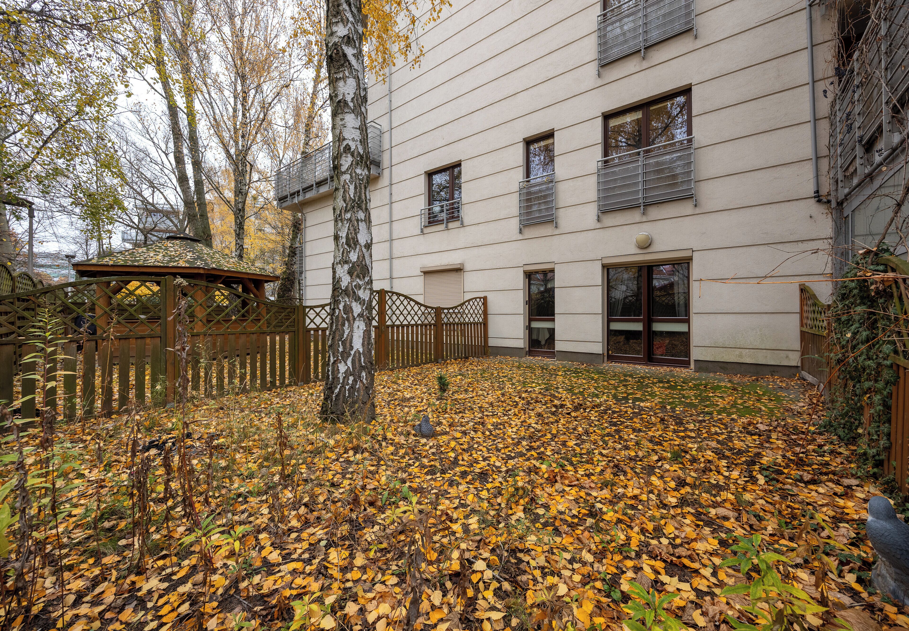 A courtyard with a gazebo, a building with multiple windows, and a wooden fence.