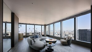 Una sala de estar moderna con un sofá modular, una mesa de centro redonda y vistas de la ciudad a través de amplias ventanas.