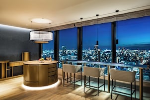 A modern bar area with a city view, a round bar, and two high chairs.