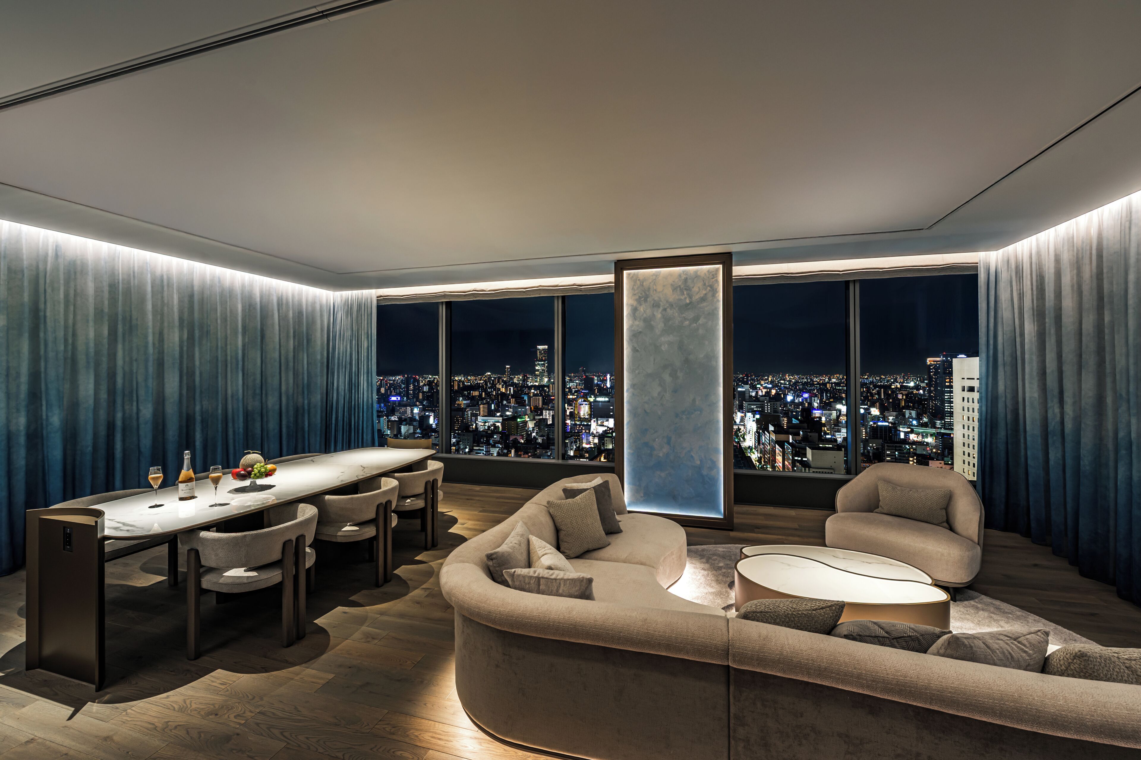 A modern living room with a curved sofa, a round coffee table, and a dining area with chairs and a table.