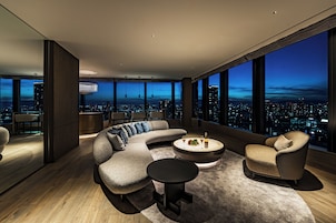 A modern living room with a curved sectional sofa, a round coffee table, and a city view through large windows.