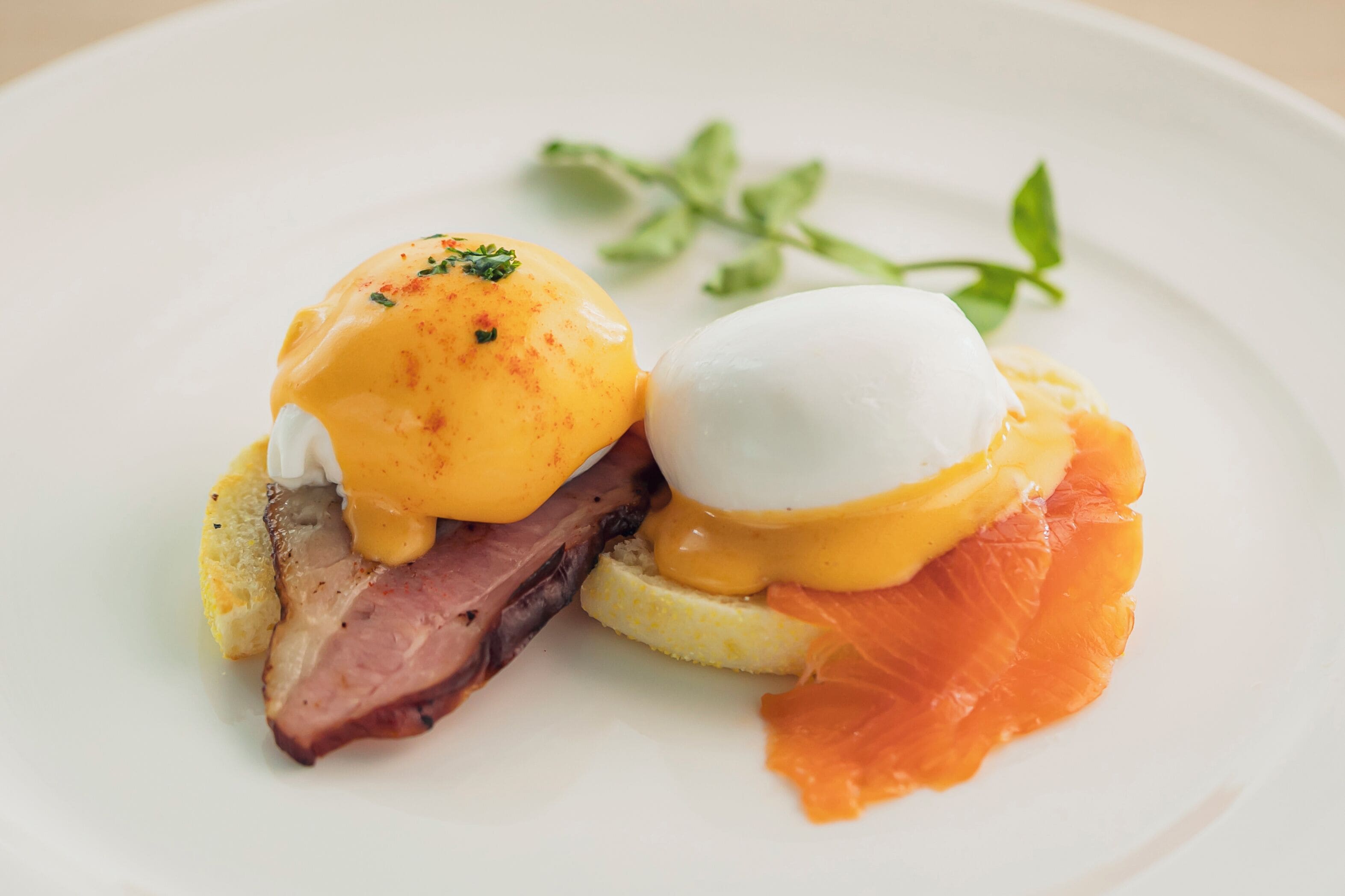 A plate with eggs benedict, smoked salmon, and ham.