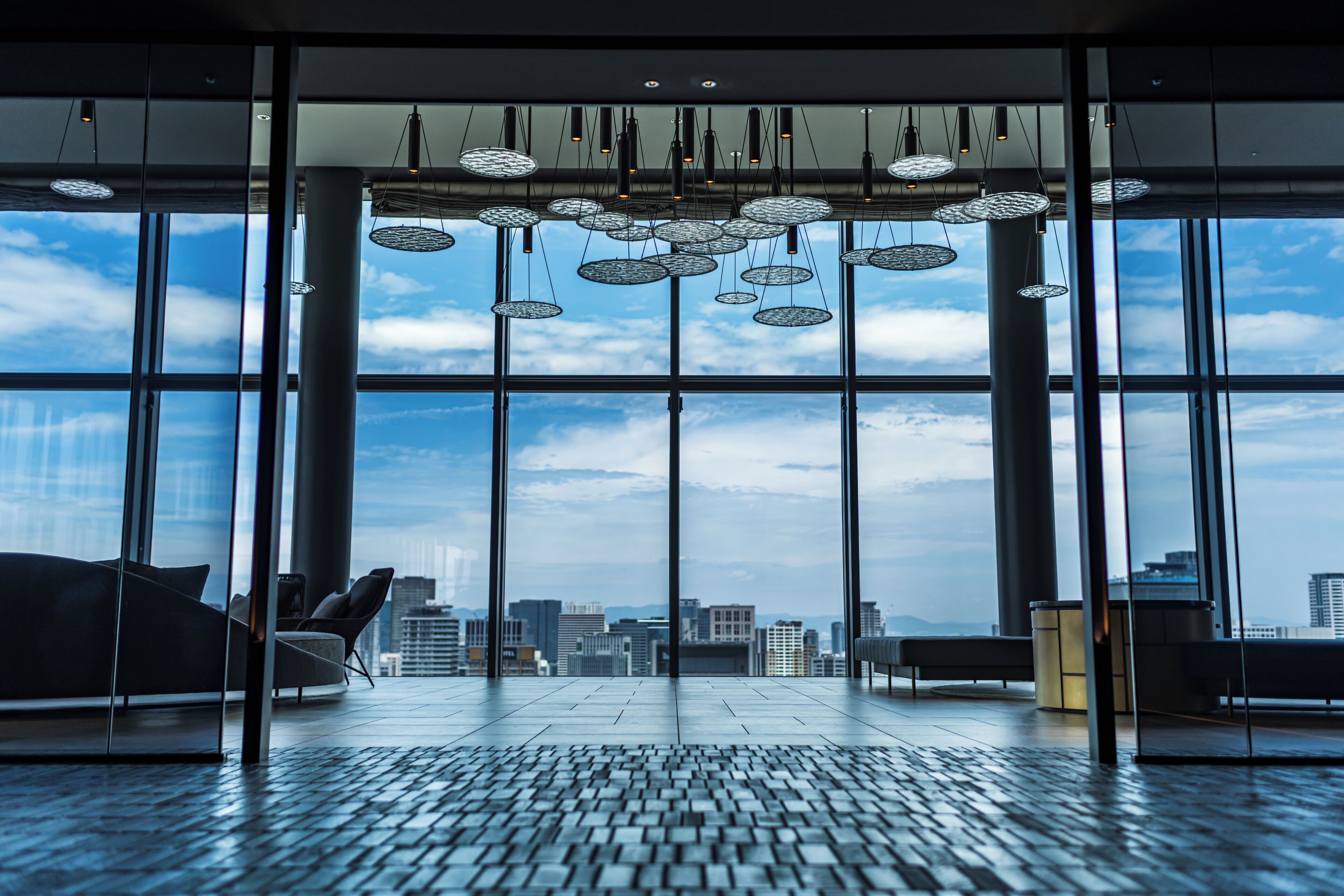 A spacious interior with large windows, a modern ceiling design, and a view of the cityscape.