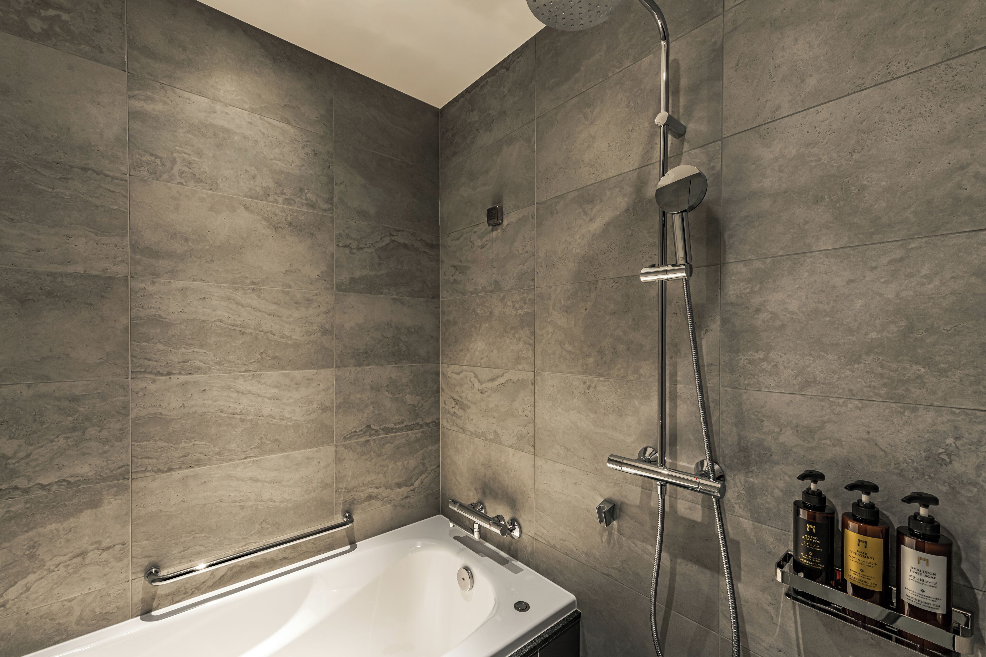 A modern bathroom with a bathtub, a shower, and a shelf with toiletries.