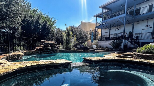 A swimming pool with clear water, surrounded by rocks and trees. - Peckham Point 5 Bd Lake View Retreat w Private Pool (Point Venture)