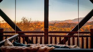 A wooden deck with a view of autumn foliage and mountains.