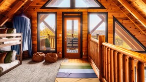 A cozy attic bedroom with a sloped ceiling, a bunk bed, a large window, and a view of the outdoors.