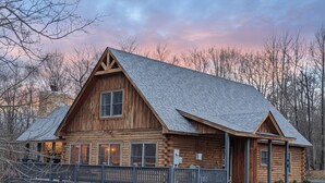 A wooden cabin with a gabled roof, a deck, and a stone chimney. - Sundance Summit: A 4 BR retreat in a Ski-in/Ski-out Community near Wisp (McHenry)