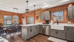 A modern kitchen with wooden walls, grey cabinets, and a central island. - Sundance Summit: A 4 BR retreat in a Ski-in/Ski-out Community near Wisp (McHenry)